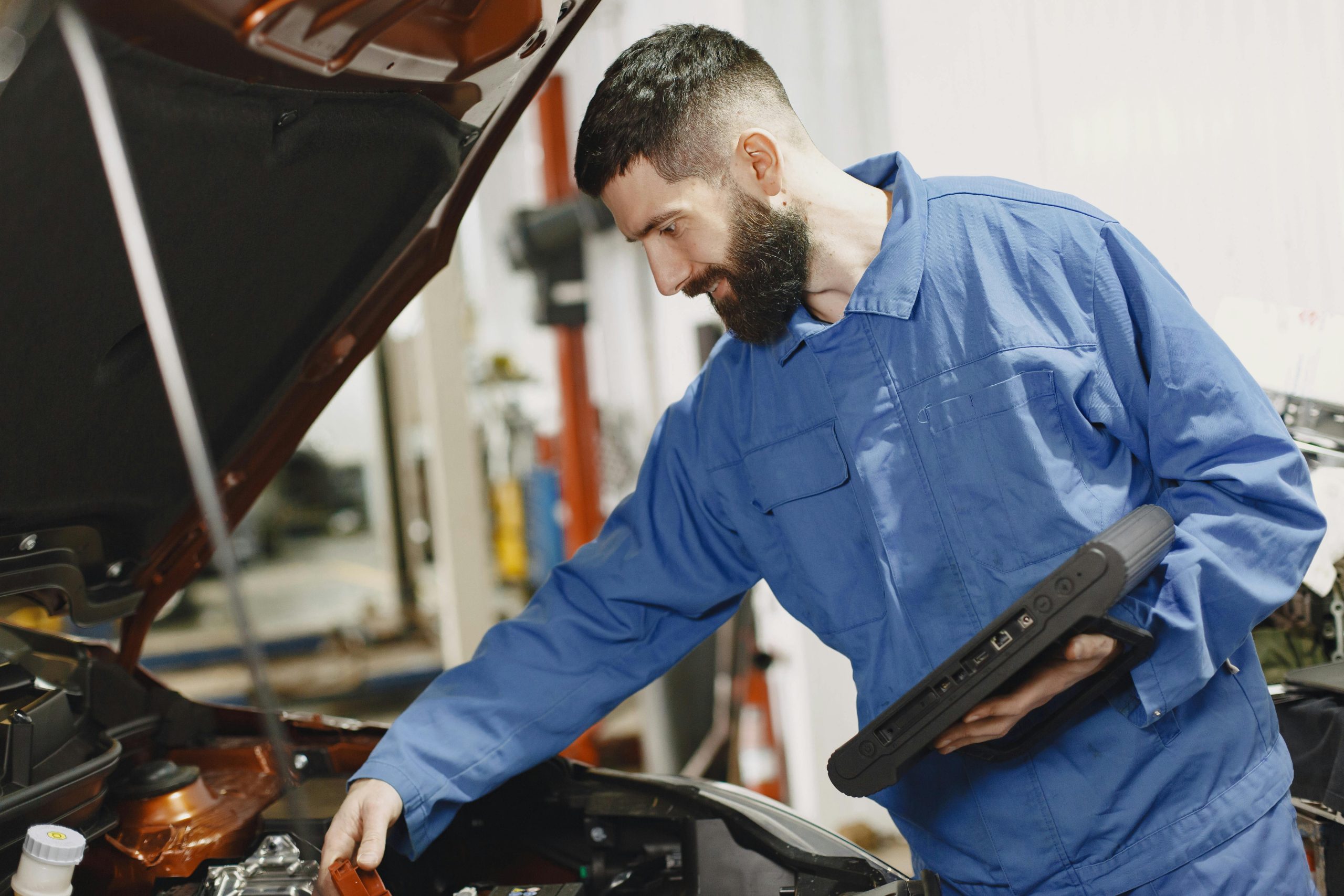 A mechanic performs a maintenance check under the hood of a vehicle.