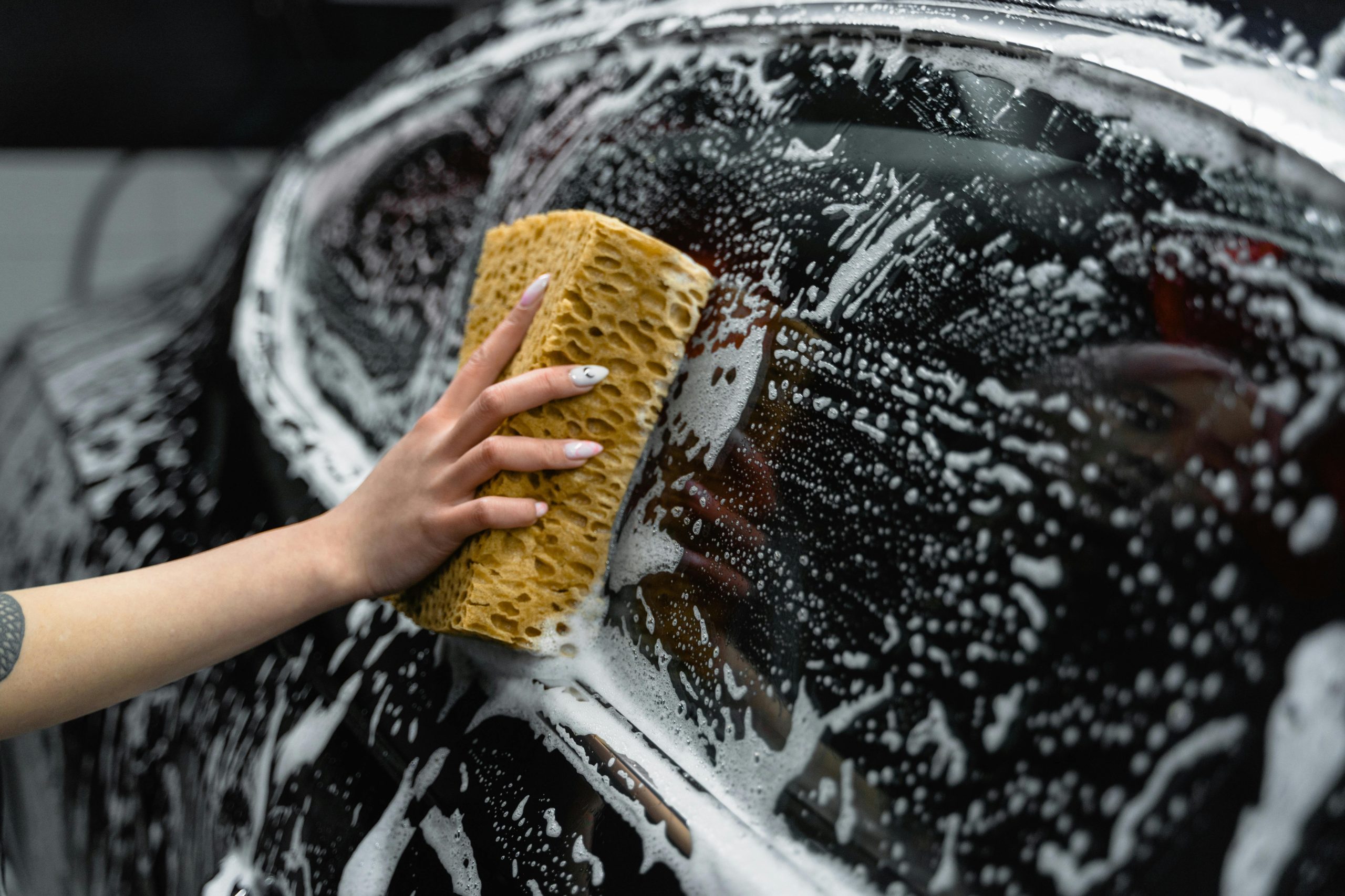 A car owner soaps down their car during a wash.