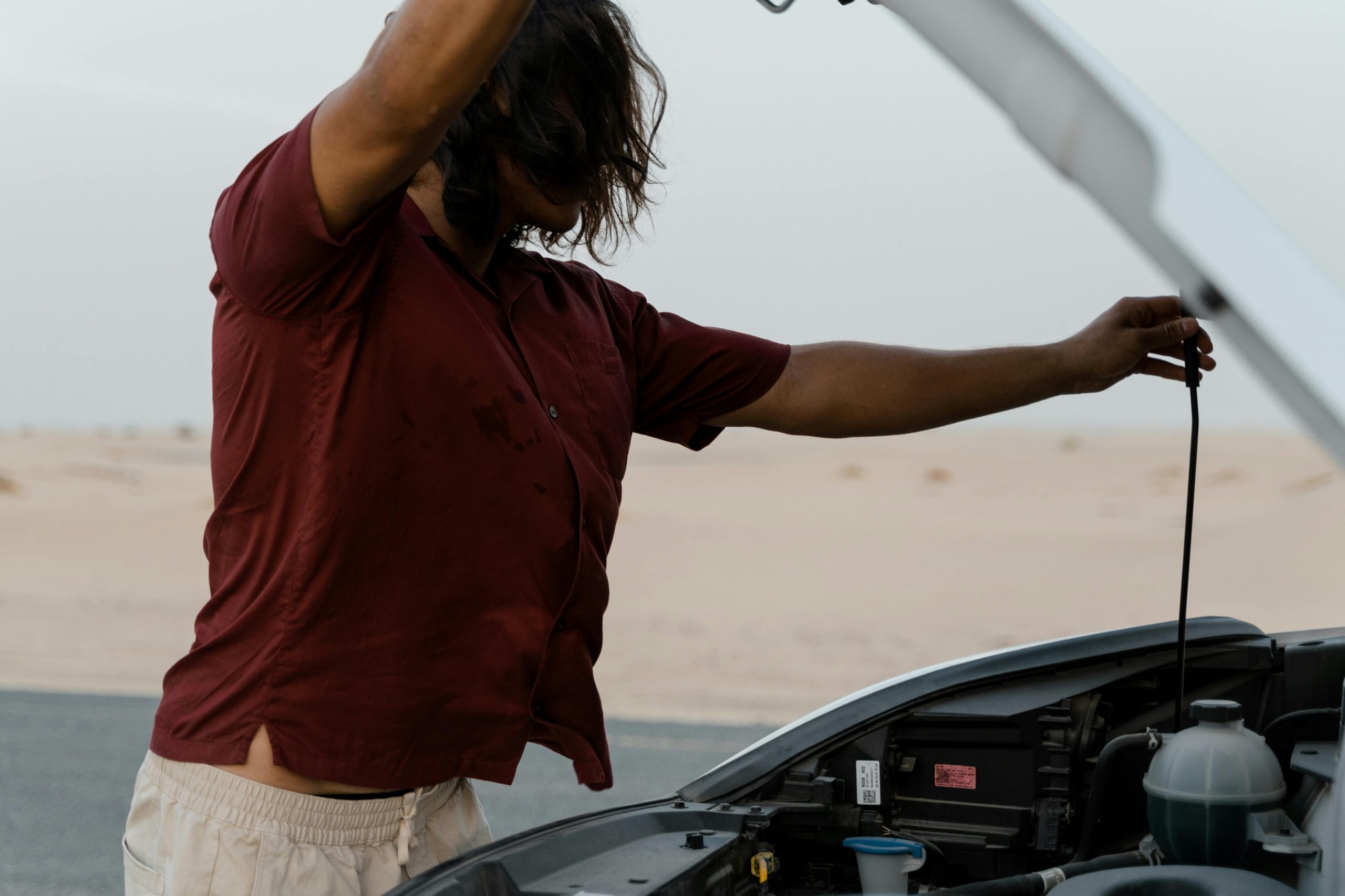 A car owner lifts the hood of his car to check his cooling system.