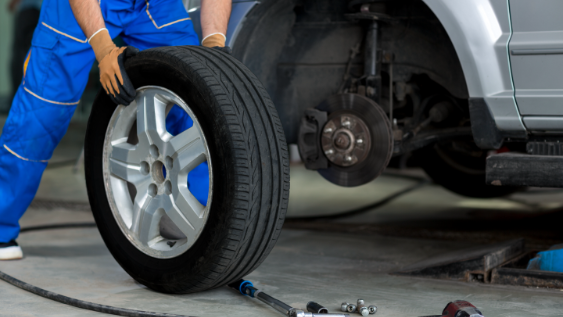 A mechanic rolls away a tire so he can fix the brakes.