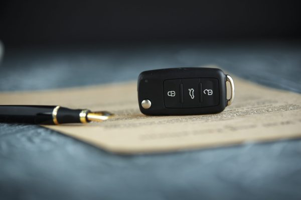 A car key sits on top of a form along with a pen.