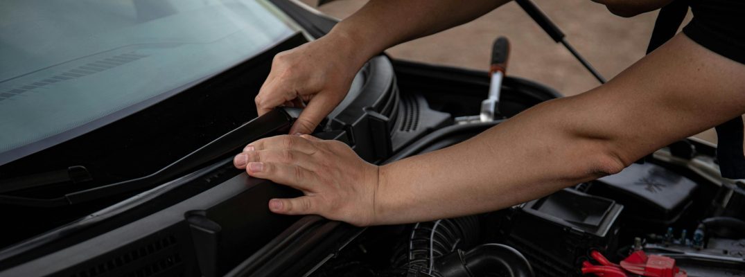 A mechanic replaces windshield wiper blades.
